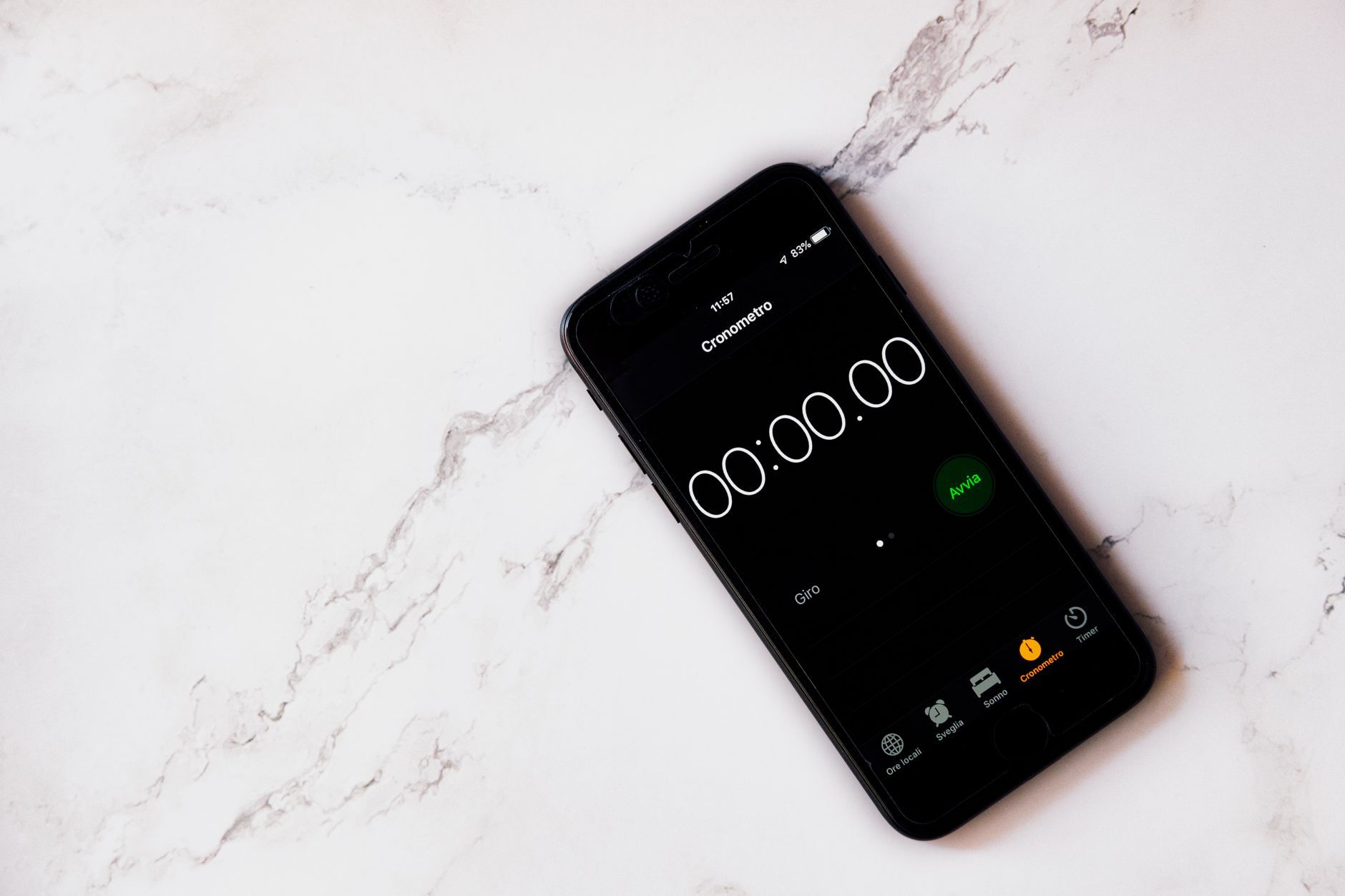 Close-up of a smartphone displaying a stopwatch on a marble surface.